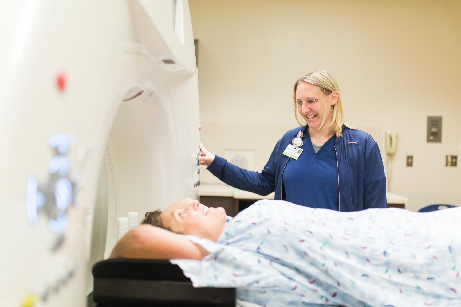 An Imaging Professional aids a patient undergoing a CT Scan