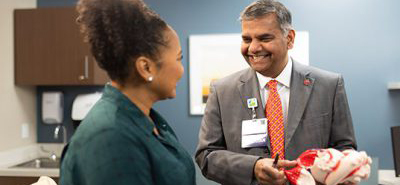 A heart doctor explains the heart to a patient using a plastic heart model figure. 