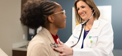 A doctor checks the lungs of a patient in a primary care office. 