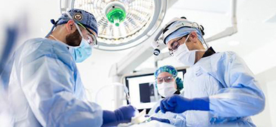 Three surgery providers operate on a patient in a hospital surgery room. 