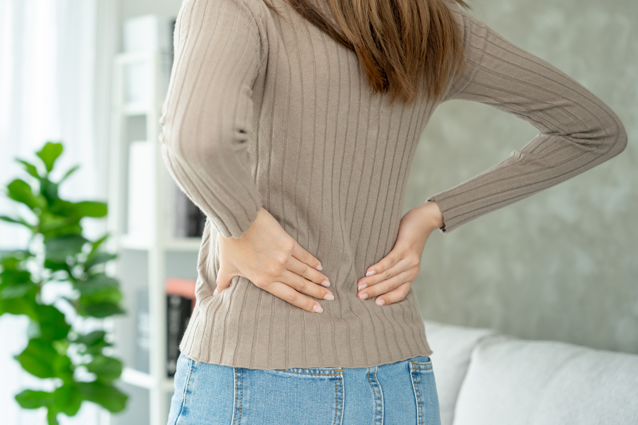 Woman holding her lower back while and suffer from unbearable pain health and problems, chronic back pain, backache in office syndrome, scoliosis, herniated disc, muscle inflammation