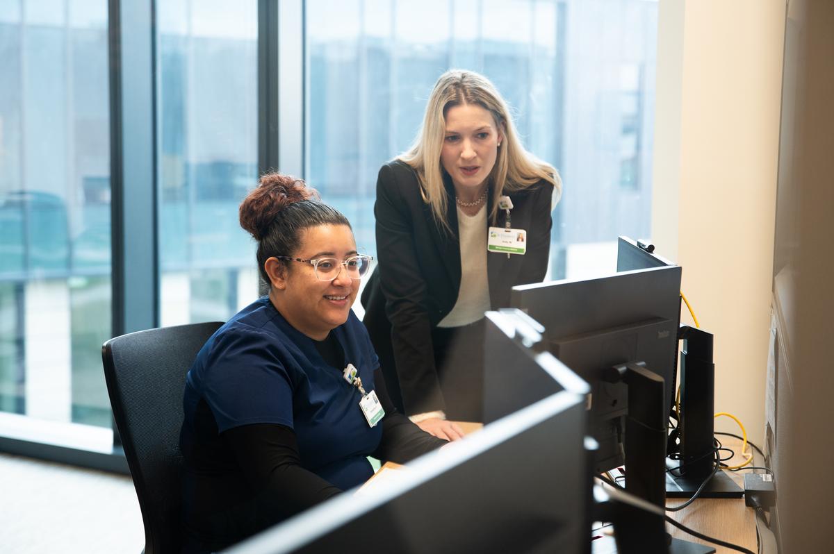 Two associates discuss information on a computer screen.