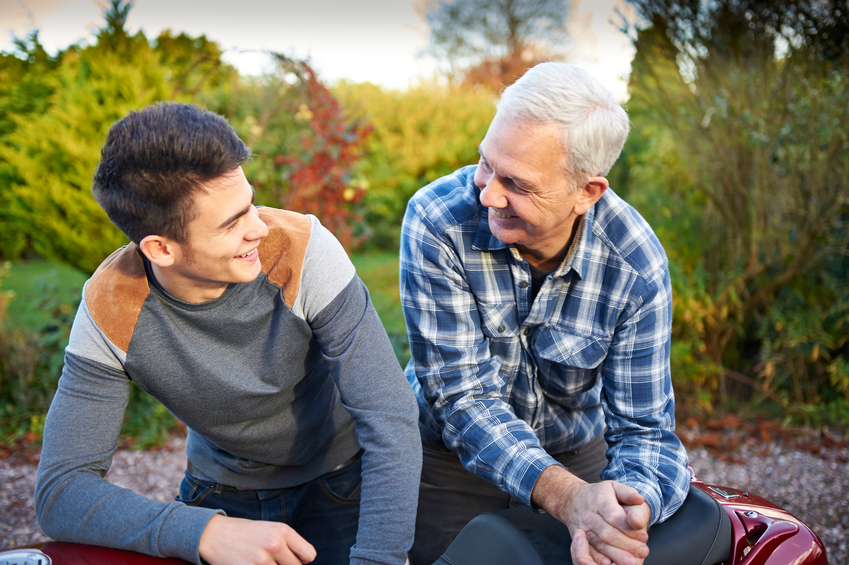 A father and son sitting and looking at each other smiling