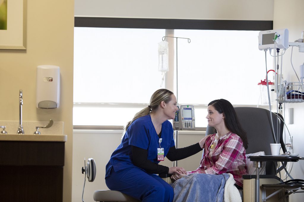 Female nurse talks with female cancer patient during chemotherapy