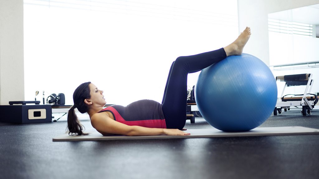 Pregnant woman with exercise ball doing pilates