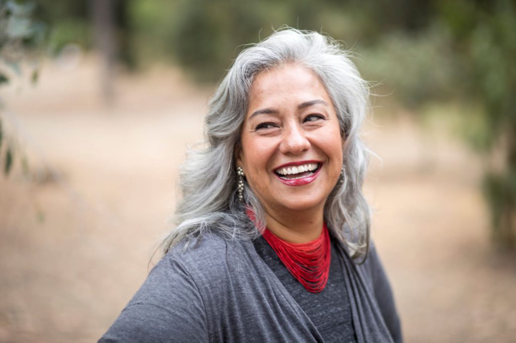 A white-haired women smiles as she walks in nature