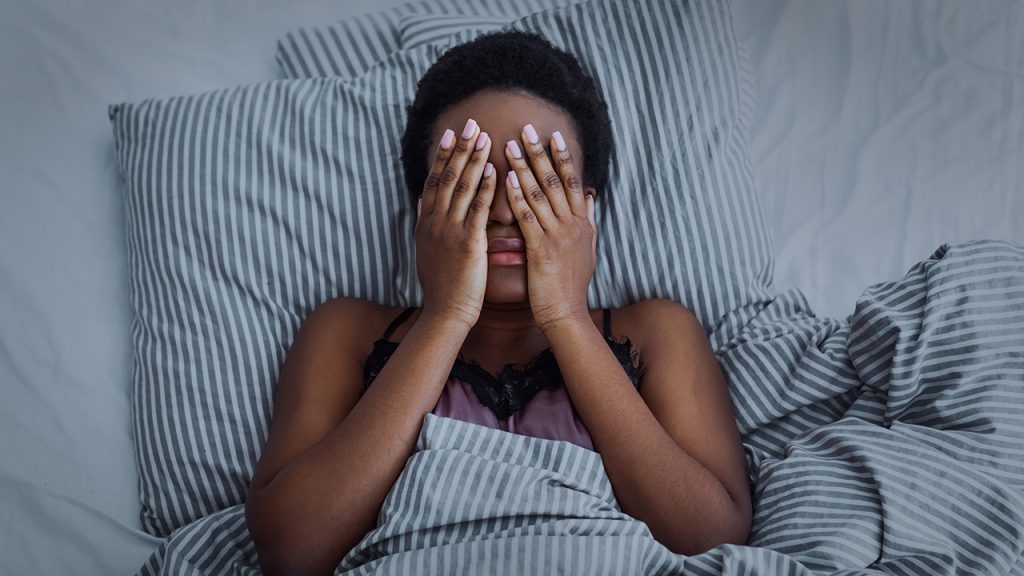 A woman lying in bed having difficulty sleeping