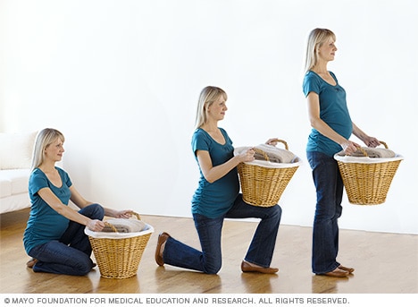 Pregnant woman lifting basket from floor